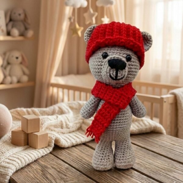 Osito de amigurumi color café/gris con gorro y bufanda roja tejida, fondo blanco y crema limpio, estilo nórdico y tierno.